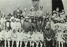 Group photograph of Black church members standing in several rows in front of the church.