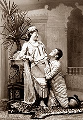 photograph of young white woman, seated, and man kneeling lovingly at her feet