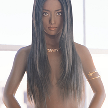 An image of recording artist Ayumi Hamasaki in front of a building window with a black wig covering her breasts. Her skin is digitally altered to make it look darker.