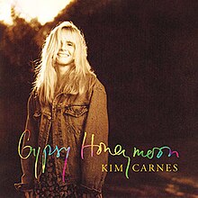 Cover artwork of "Gypsy Honeymoon" showing Carnes wearing a dress and denim jacket, smiling at the camera