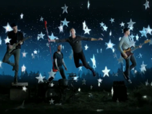 A group of four men with musical instruments float in the air assisted by cables