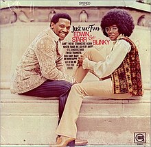 Blinky and Edwin Starr seated on steps across from one another, turning to look toward the camera