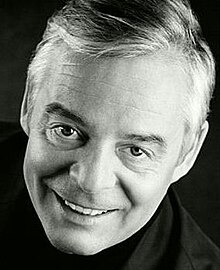 Publicity shot of a smiling, clean-shaven man, with short hair.