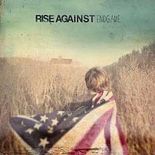 The cover art for Endgame. The cover features a picture of a boy who's back is turned to the camera. The boy is draped in an American flag, and is standing in a wheat field. The words "RISE AGAINST ENDGAME" are displayed in the top of the image.