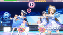 The player is playing "Yume no Tobira" with four buttons, hitting Perfects. The heads-up display features the Clear Gauge on the top-left, which is currently near the B Rank. Their score, currently has 18855 points, is on the top-right. And the stars with individual alphabet which would spell out "Love Live!", currently has "L O V E L I", is at the top. The 3D animated music video in the background, which Kotori, Nozomi, Umi, and Rin are performing in its respective costume set on the rooftop in the city.