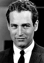 Black and white headshot of a man wearing a coat, shirt, and tie