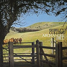 A pastoral scene with horses walking toward green hills