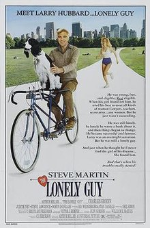 A man riding a bicycle with a dog balanced in front, and a woman runs behind them.