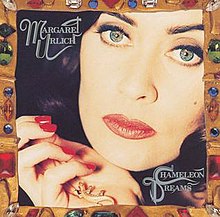 Main image is a close up of the artist's face with a hand near her chin. Her name in stylised capitals is at top left, while the album title in similar style is at bottom right. The whole area is bordered in various objects including buttons, gemstones and piecework.