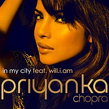 Фотография, показывающая лицо молодой индийской женщины из профиля слева на черном фоне. Внизу изображения слова «In My City feat. Will.i.am» и «Priyanka».