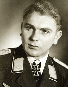 The head and shoulders of a young man, shown in semi-profile. He wears a military uniform with an Iron Cross displayed at the front of his white shirt collar. He is looking to the right of the camera.