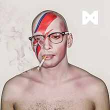 A shirtless, bald man, seen from the chest up wearing sunglasses and smoking a cigarette in front of a white background. Painted on his face is a red lightning strike. In the top right is the symbol ⋈.