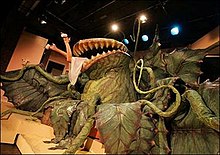 An elaborate large model of the Audrey monster resembling a mammoth Venus flytrap devouring a woman whose legs are sticking out of its mouth