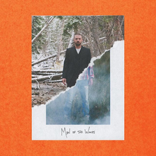 The cover image features two images of a male, edited to appear as one. Top-diagonal-half image features male in all-black suit and white undershirt, in a snow-covered wooded area. Bottom-diagonal-half image features male in ripped blue jeans, flannel button down shirt in a smog-filled wooded area. Below this title: MAN OF THE WOODS, appears in capitalised handwritten print.