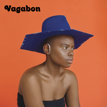 Vagabon looks off into the distance. She is wearing a blue hat. The background is orange.
