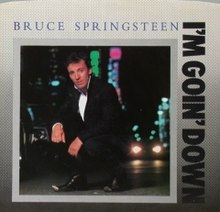 Cover of Bruce Springsteen single showing the singer wearing a black suit and crouched in front of a dark urban background