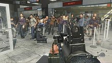 A screenshot taken from the level. The player is holding a gun and is aiming it at a large group of civilians. Bullets can be seen coming from other gunmen offscreen.