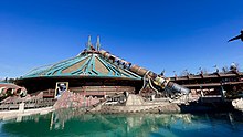 Bâtiment conique bleu et doré devant un lagon dans lequel se trouve un sous-marin.