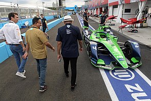 Gubernur DKI Jakarta Anies Baswedan (tengah), bersama Ketua Pelaksana Jakarta ePrix Ahmad Sahroni (kanan) dan Chief Championship Officer Formula E Alberto Longo (kiri) meninjau paddock tim balap Formula E di Jakarta International E-Prix Circuit (JIEC). Mereka melewati mobil pembalap Robin Frijns dari tim Envision Racing