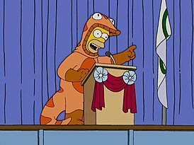 Гомер в костюме «Саламандры безопасности» на дебатах