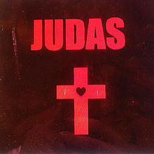 "Judas" is written in capital red letters on a black background. Below is a red cross with a black heart in the middle.