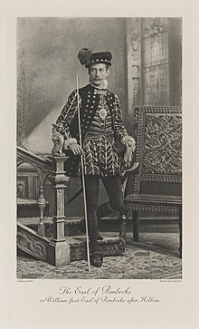 Black-and-white photograph of a standing man richly dressed in an historical costume