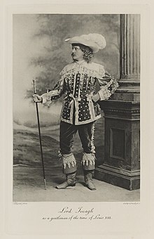 Black-and-white photograph of a standing man richly dressed in an historical costume with a stick, large hat with a plume, and high boots with lace at the top