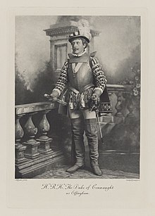 Black-and-white photograph of a standing man richly dressed in armor and a historical costume
