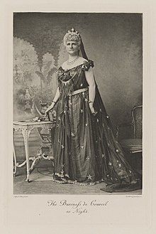 Black-and-white photograph of a standing woman richly dressed in a historical costume with stars on it