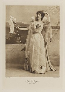 Black-and-white photograph of a standing woman dressed in an historical costume with symbols of the sun