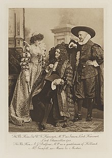 Black-and-white photograph of a standing woman and man and a seated man richly dressed in an historical costumes