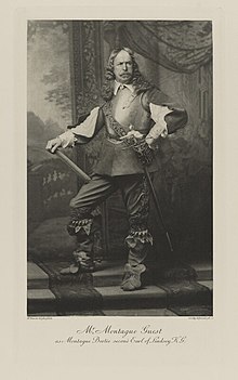Black-and-white photograph of a standing man richly dressed in an historical costume of armor, high boots, and a sword