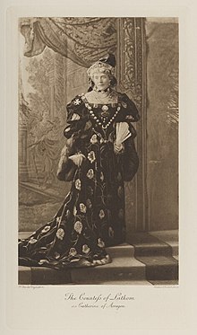 Black-and-white photograph of a standing woman richly dressed in an historical costume with a fan