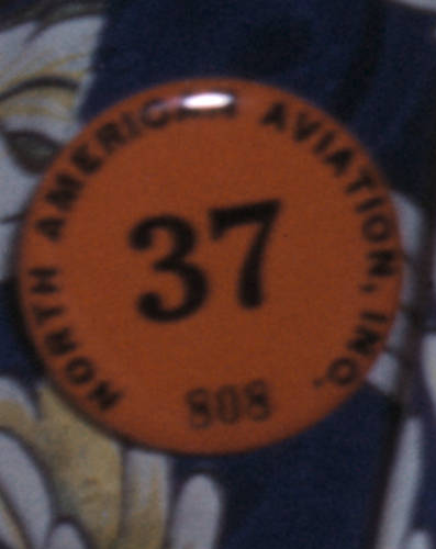 File:"37" "NORTH AMERICAN AVIATION, INC." "808" badge detail of employee number 37, Clerk in a stock rooms of North American Aviation checking the numbers of parts - Inglewood Cal (cropped).jpg