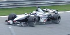 a grey open wheeled racing car drives around a track