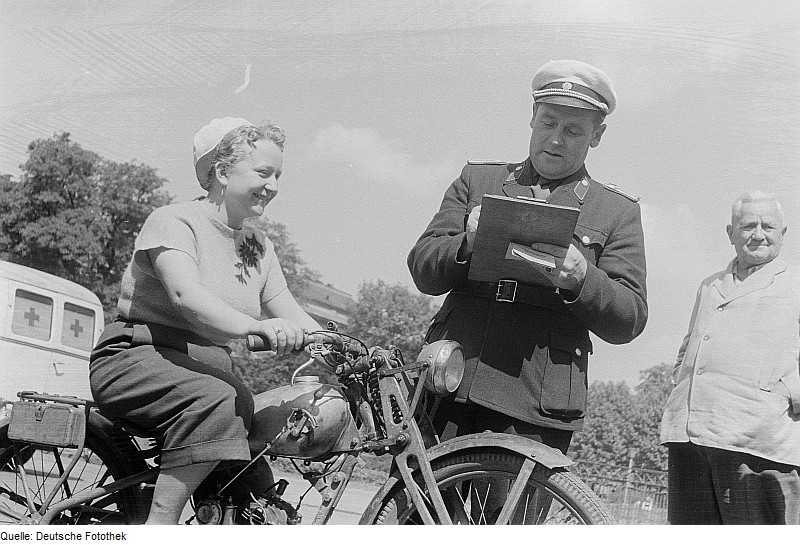 File:Fotothek df roe-neg 0006710 023 Eine Frau auf einem Motorrad, ein Polizist mit einem Klemmbrett sowie ein weiter.jpg