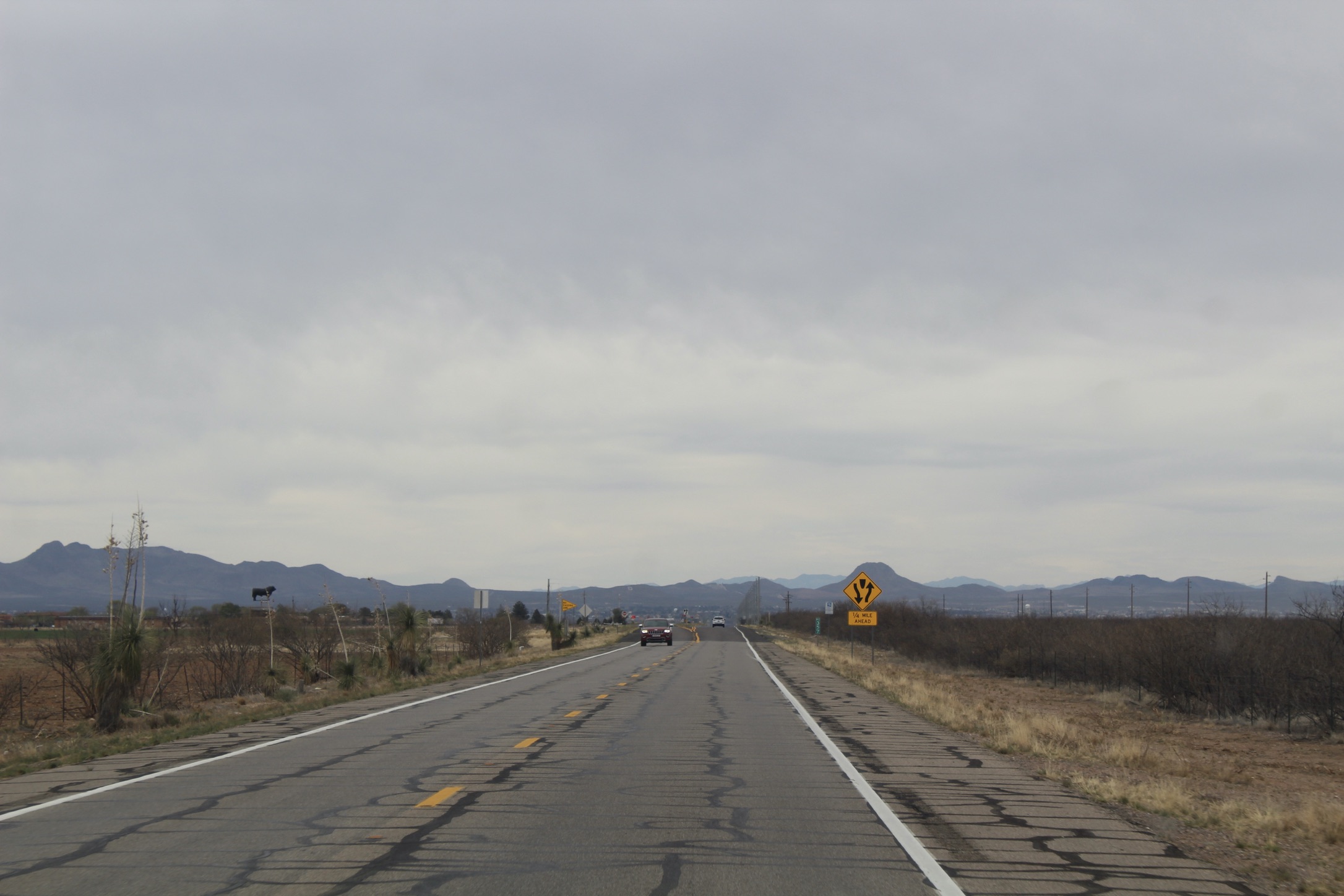 A patched up highway with one lone car on it