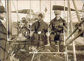 Katharine with brother Wilbur seated in the Wright Model A Flyer with other brother Orville standing nearby in 1909. This was Katharine's first time flying.