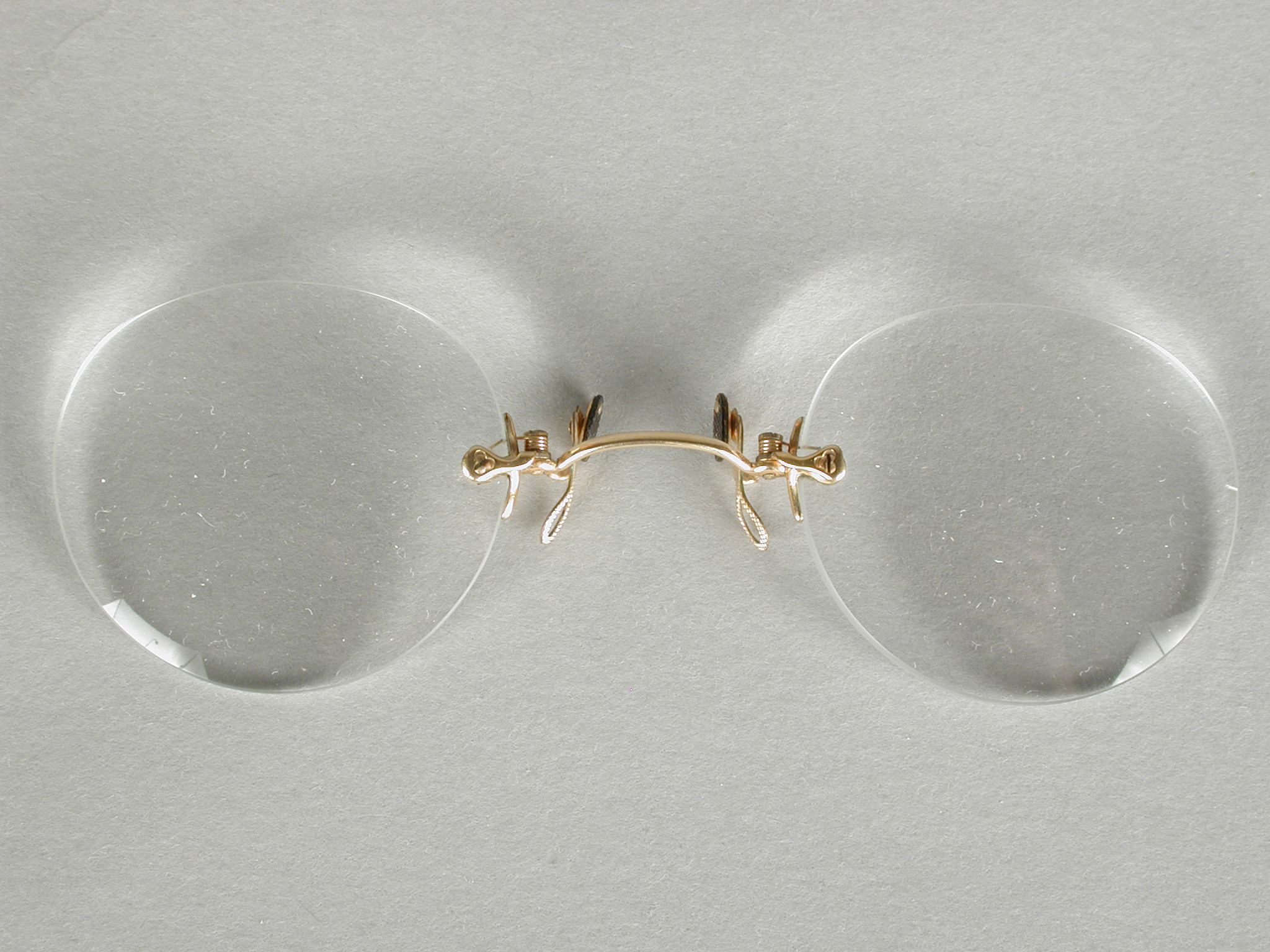 Knijpbril of pince-nez met vrijwel ronde glazen op sterkte zonder montuur, met...