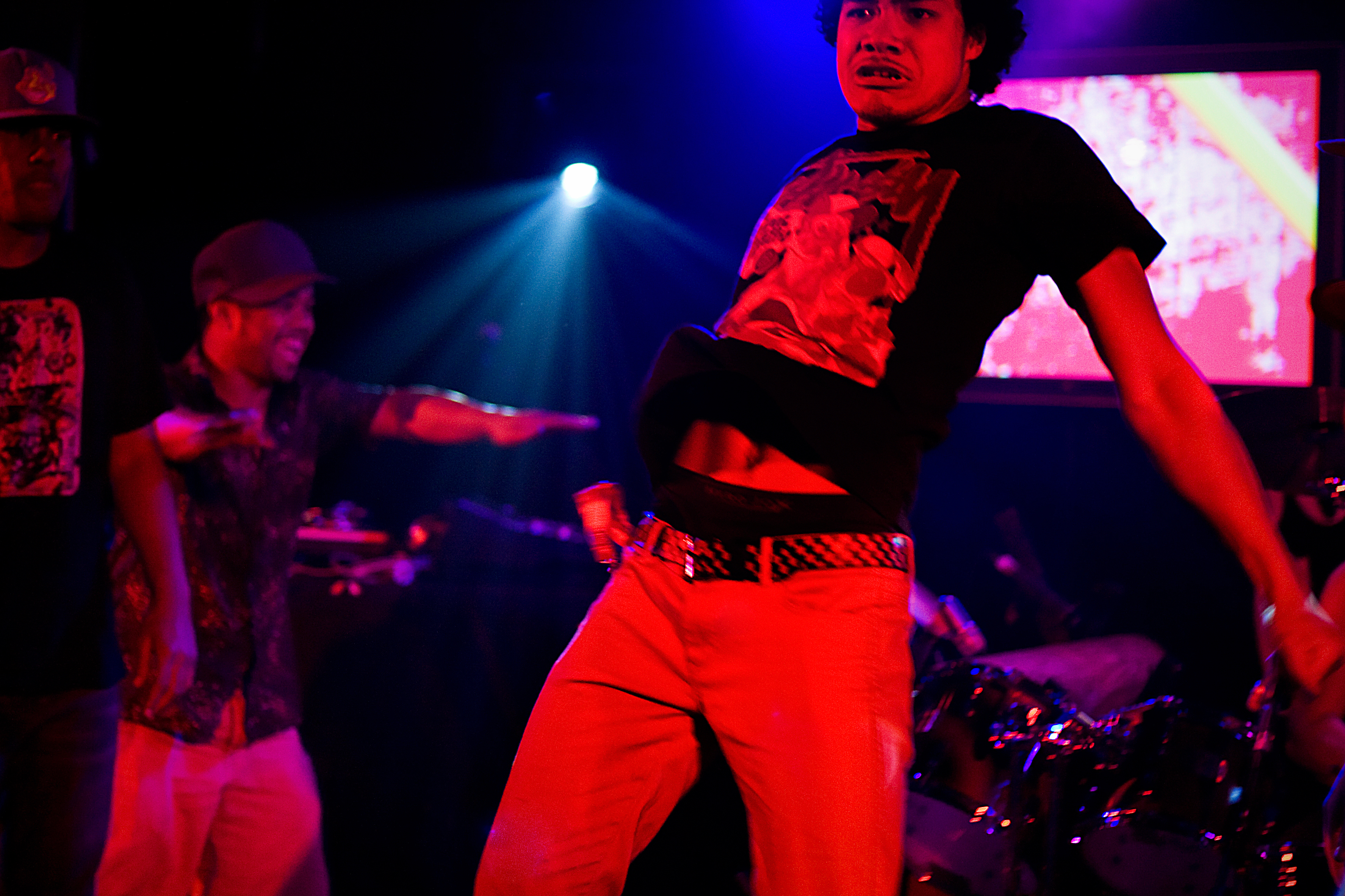 Man performs in front of crowd with red, blue, and purple mood lighting