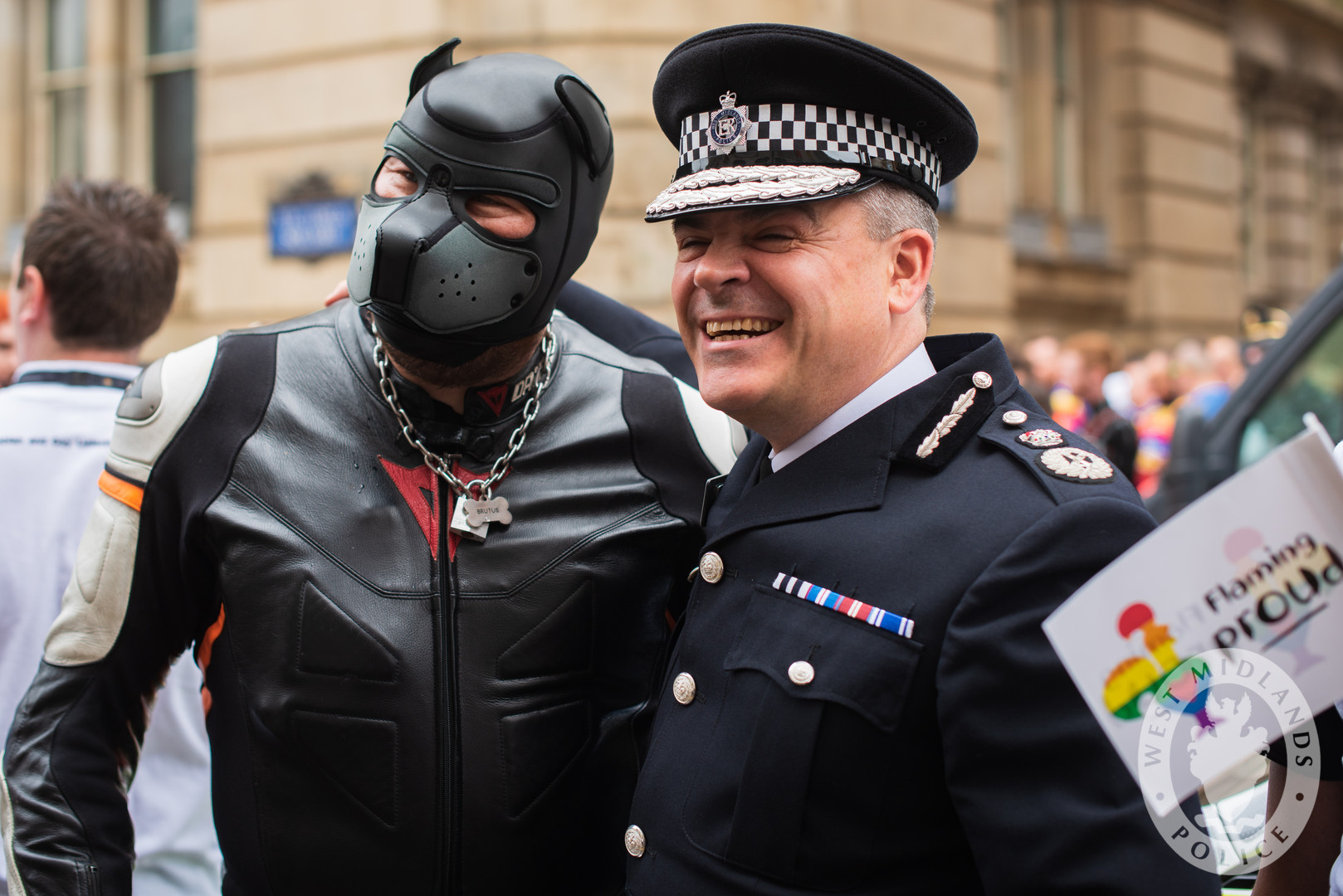 Police officer with arm around man in puppy play outfit at Pride.