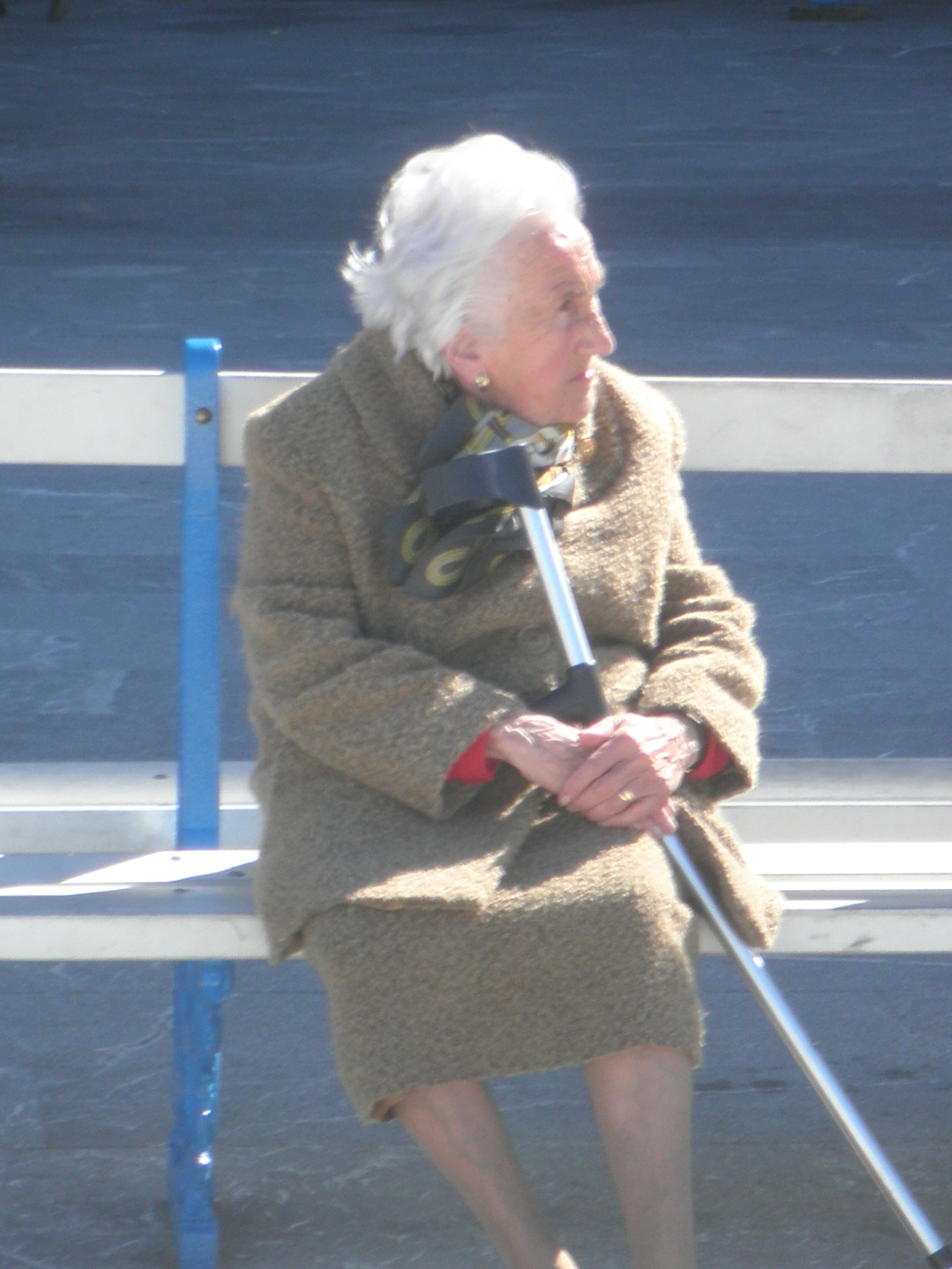 An Elderly Woman Sits Outside In The Cold.