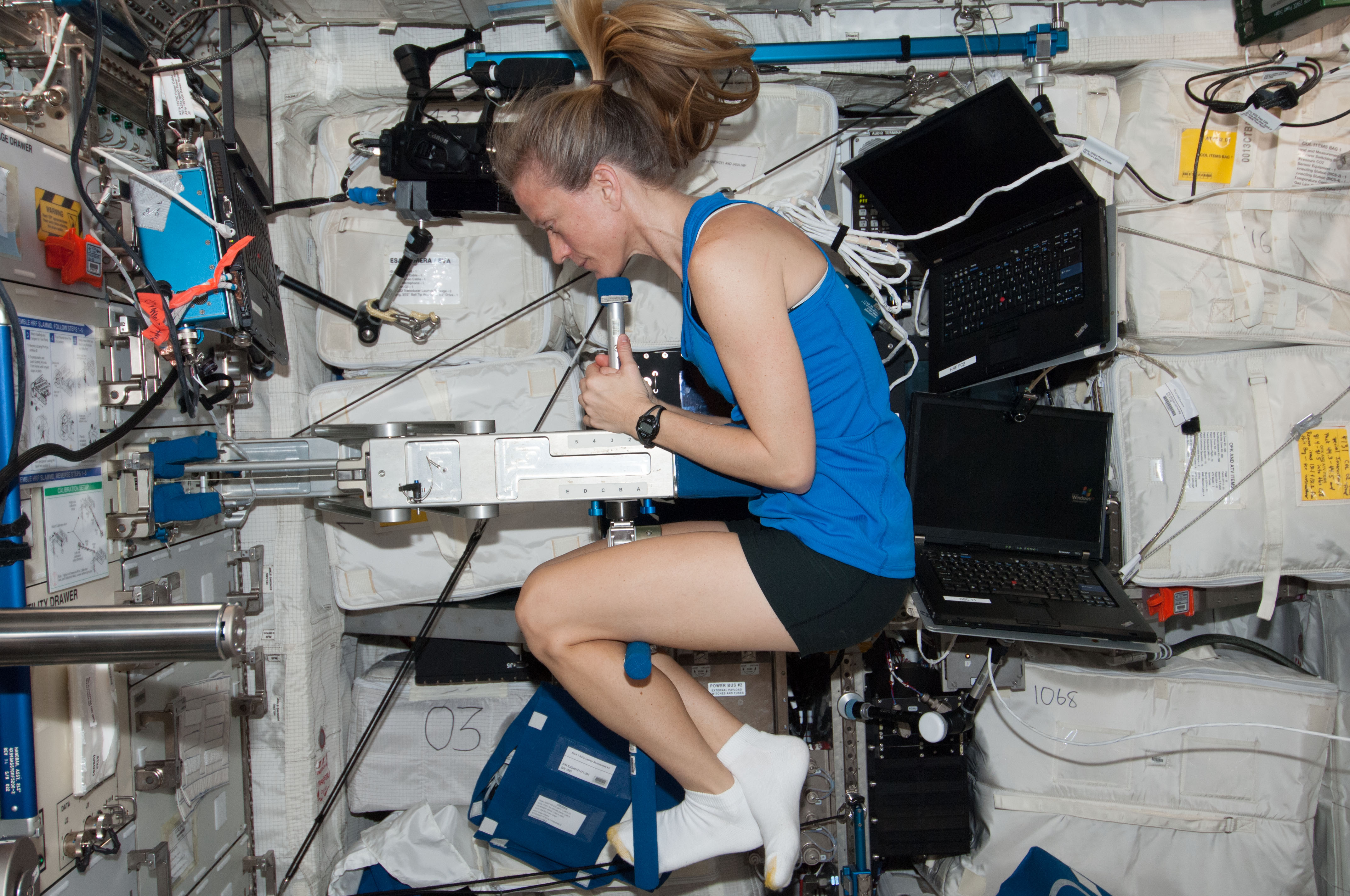Астронавт НАСА Карен Найберг измеряет показатели здоровья и массу тела.