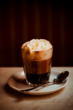 Einspänner Coffee: A viennese specialty. It is a strong black coffee served in a glass topped with whipped cream, it comes with powder sugar served separately.