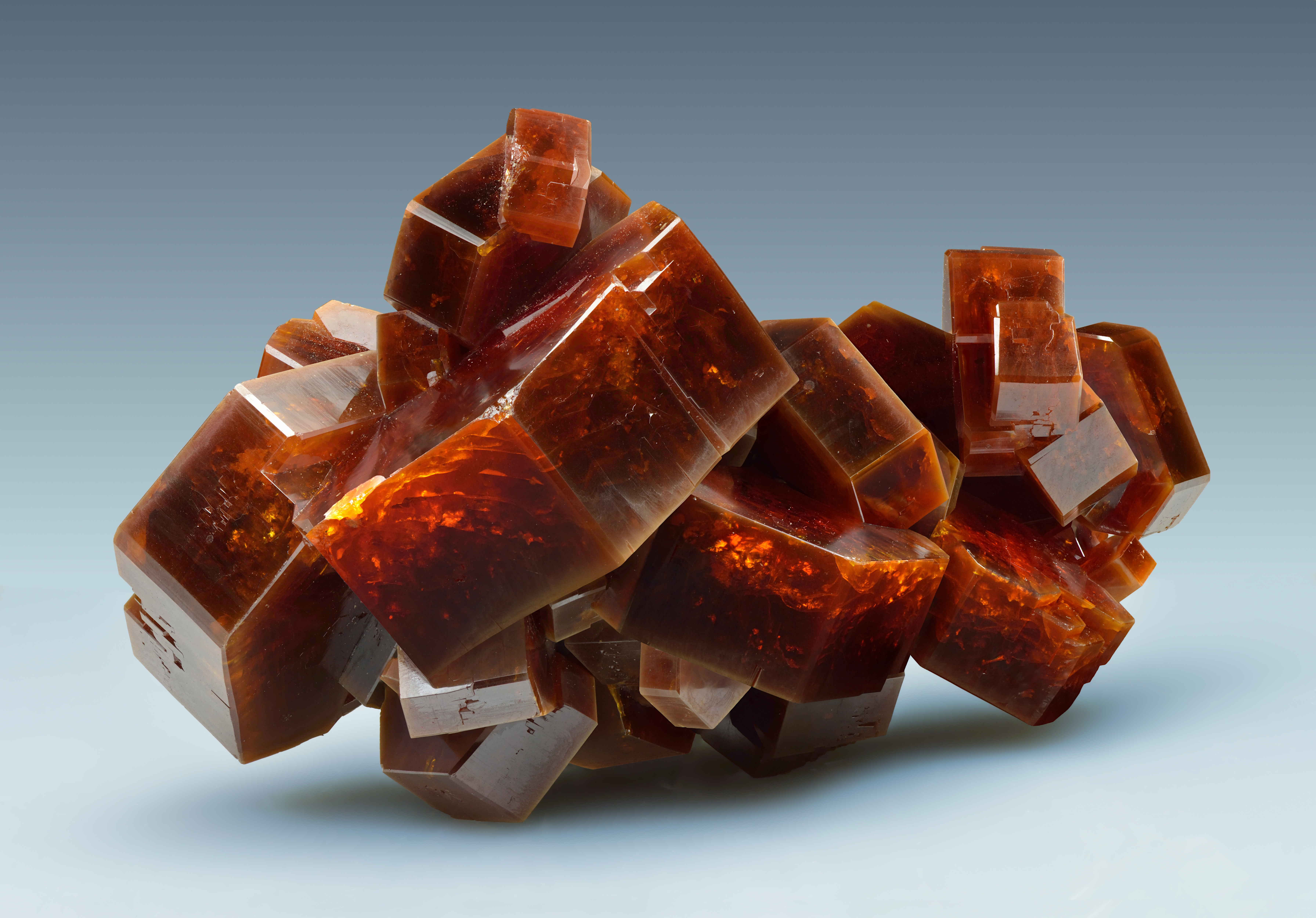 The mineral vanadinite, which has notably hexagonal-shaped crystals that group together in clusters. The mineral is orange-red in color.