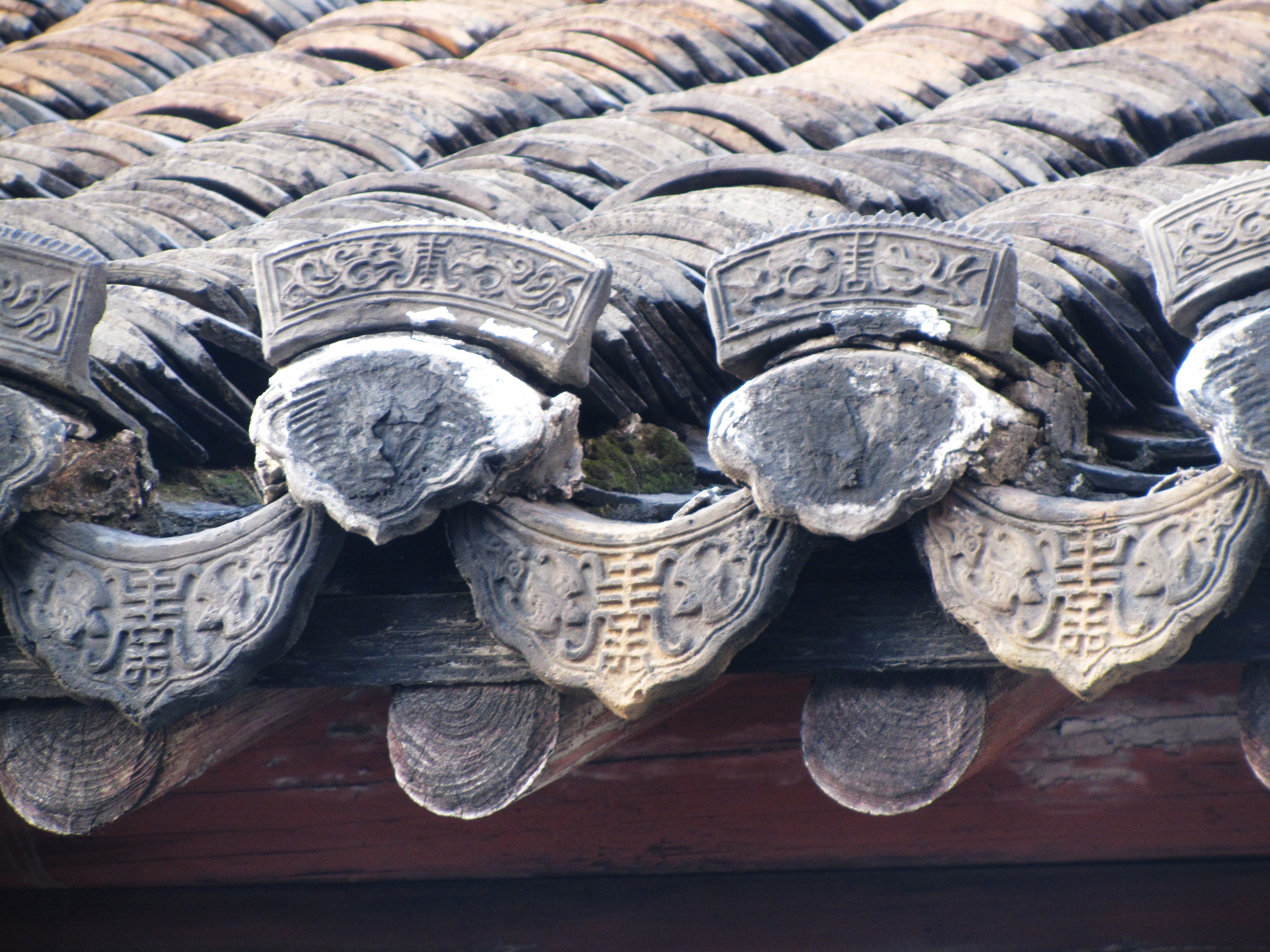 Overlapping glazed roof tiles with inscribed characters.