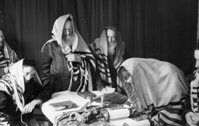 Juden mit ihrem Rabbi beim Gebet. Der Vorbeter liest aus der gerollten Thora, dem ersten geschriebenen Gebets- und Gesetzbuch des Judentums.