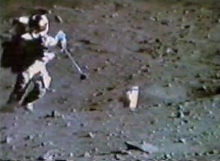 TV camera still of Charlie Duke's "juggling act" trying to catch sample 62275 at the rim of Buster crater. The sample is to the right of his helmet and above his outstretched hands. Charlie Duke Buster crater juggling.jpg