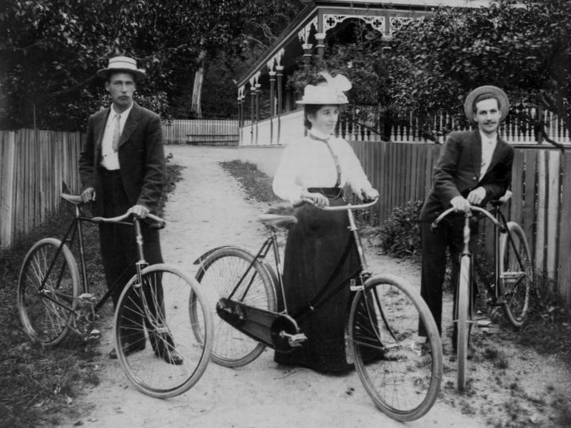 Female cyclist with step through bike and two male cyclists with step over bike in Thames, New Zealand, around 1895