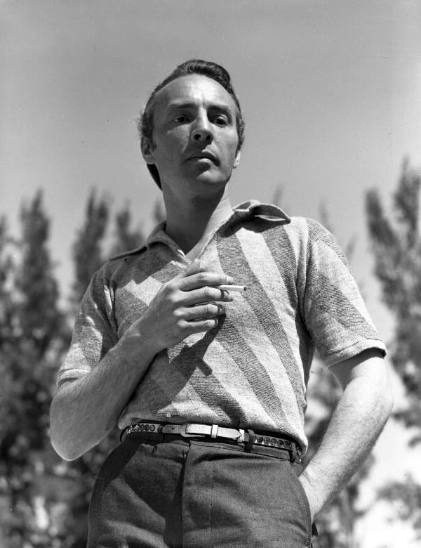 George Balanchine standing, cigarette in hand, photographed from a low viewpoint